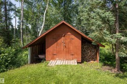 A-frame storage shed with double doors, wood siding, and an attached covered wood storage area - 