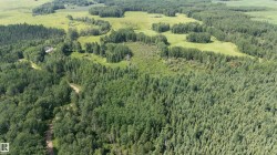 Expansive aerial view showcasing a large parcel of wooded land with interspersed clearings - 