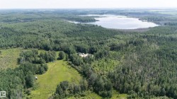 Expansive wooded landscape featuring a substantial body of water, open clearings, and dense forest - 