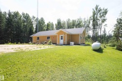 Single-story home featuring light yellow siding, a dark shingle roof, and white trim - 