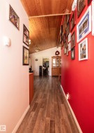 Hallway featuring wood-finish flooring, a vaulted wood-paneled ceiling, and a bright red accent wall - 
