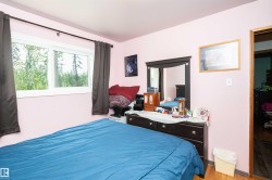 Room featuring a large window with white casing, light-toned wood-finish flooring, and a dresser with an attached mirror - 