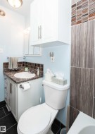 Bathroom featuring a vanity with a drop-in sink and a patterned countertop, a wall-mounted medicine cabinet, and an overhead storage cabinet - 