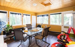 Room featuring wood-finish flooring, multiple windows, a wood-paneled ceiling, and a white exterior door with a glass panel - 