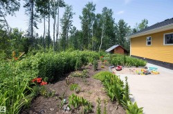 Expansive garden bed featuring established plantings and flowering perennials alongside a concrete patio - 