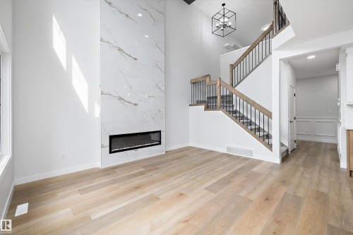 Soaring ceilings complement the full-height fireplace featuring a linear electric insert and large format porcelain tile - 919 Elderberry Landing Nw, Edmonton, AB - Indoor With Fireplace