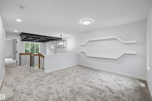 Carpeted space featuring a geometric wall display, recessed lighting, and a modern ceiling fixture - 919 Elderberry Landing Nw, Edmonton, AB - Indoor Photo Showing Other Room