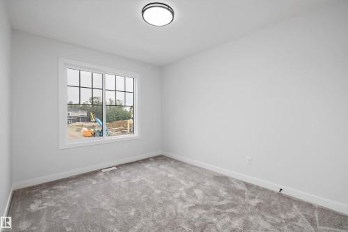 Bright room with soft gray carpeting, white baseboards, and neutral wall paint - 919 Elderberry Landing Nw, Edmonton, AB - Indoor Photo Showing Other Room