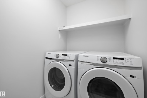 Dedicated laundry area featuring a white wall shelf, light neutral wall paint, and baseboard trim - 919 Elderberry Landing Nw, Edmonton, AB - Indoor Photo Showing Laundry Room