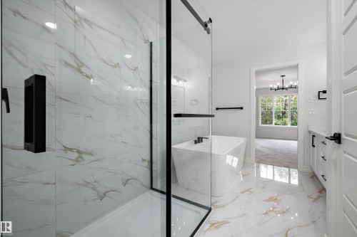 Spacious bathroom featuring a frameless glass shower enclosure with black hardware, a freestanding soaking tub with black fixtures, and a white vanity with black hardware - 919 Elderberry Landing Nw, Edmonton, AB - Indoor Photo Showing Other Room