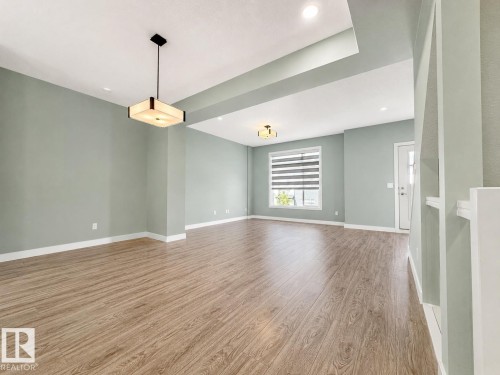 Spacious interior featuring wood-finish flooring, recessed lighting, and a contemporary ceiling fixture - #56 804 Welsh Dr Sw, Edmonton, AB - Indoor Photo Showing Other Room