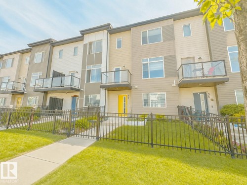 Modern multi-story townhouse exterior featuring multiple balconies with glass railings - #56 804 Welsh Dr Sw, Edmonton, AB - Outdoor With Balcony