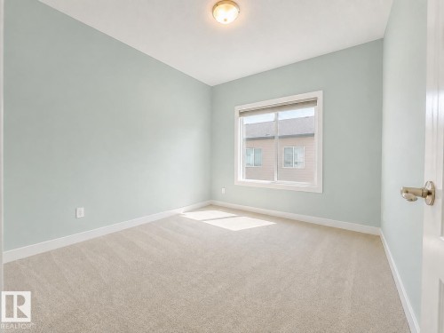 Neutral tone wall paint, window with white trim, beige carpet flooring, recessed ceiling light fixture, and white painted door - #56 804 Welsh Dr Sw, Edmonton, AB - Indoor Photo Showing Other Room