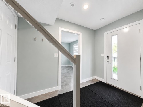 Entryway featuring a white front door with a vertical window, recessed lighting, and light grey walls - #56 804 Welsh Dr Sw, Edmonton, AB - Indoor Photo Showing Other Room