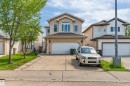 Stucco exterior residence featuring an arched window, multiple vertical windows, attached two-car garage, and concrete driveway - 16205 55 Street Nw, Edmonton, AB  - Outdoor With Facade 