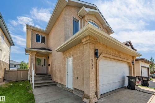Stucco exterior with an integrated two-car garage featuring a white panel door - 16205 55 Street Nw, Edmonton, AB - Outdoor
