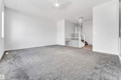Spacious interior room featuring plush gray carpeting, white painted walls, and a ceiling fan with integrated lighting - 