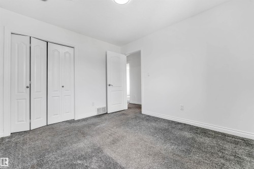 Spacious room featuring neutral grey carpet flooring and white painted walls - 16205 55 Street Nw, Edmonton, AB - Indoor Photo Showing Other Room