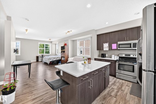 Open-concept living space featuring a central kitchen island with seating - #10 2803 James Mowatt Trail Sw, Edmonton, AB - Indoor Photo Showing Kitchen With Stainless Steel Kitchen