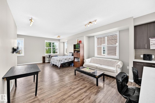 Open-concept living area featuring wood-finish flooring, multiple windows, and recessed lighting - #10 2803 James Mowatt Trail Sw, Edmonton, AB - Indoor Photo Showing Living Room