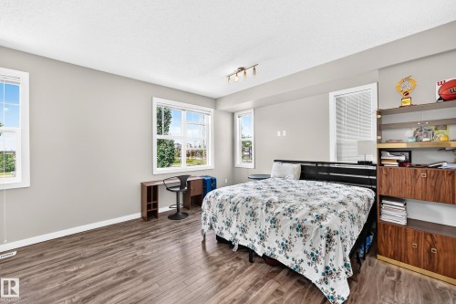 Spacious room featuring abundant natural light from multiple windows, wood-finish flooring, and a neutral wall color palette - #10 2803 James Mowatt Trail Sw, Edmonton, AB - Indoor Photo Showing Bedroom
