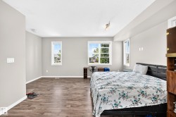 Spacious interior featuring wood-finish flooring, multiple windows, and light gray wall tones - 