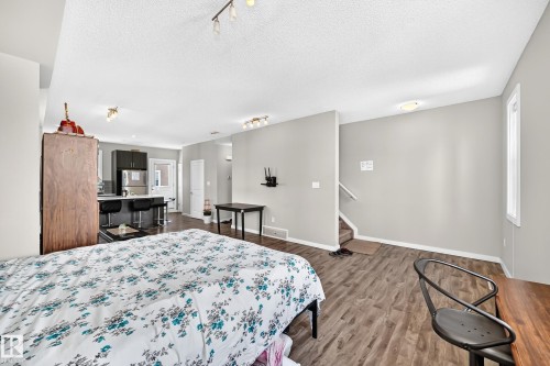 Open concept living area featuring wood-finish flooring, light gray walls, and white trim - #10 2803 James Mowatt Trail Sw, Edmonton, AB - Indoor Photo Showing Bedroom