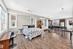 Open-concept living space featuring wood-finish flooring, recessed lighting, and multiple windows - 