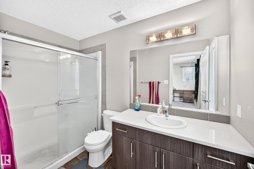Bathroom featuring a glass-enclosed shower, a vanity with a white countertop and integrated sink, a large wall-mounted mirror, and a three-light fixture - #10 2803 James Mowatt Trail Sw, Edmonton, AB - Indoor Photo Showing Bathroom