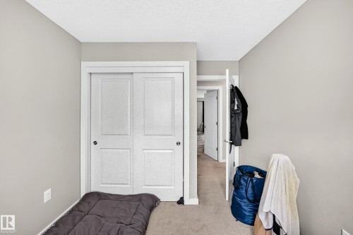 Bedroom featuring a sliding double-door closet, neutral-toned walls, and carpet flooring - #10 2803 James Mowatt Trail Sw, Edmonton, AB - Indoor