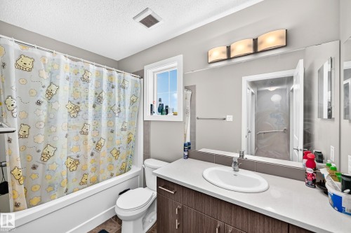 Bathroom featuring a white bathtub, toilet, and a vanity with an integrated sink - #10 2803 James Mowatt Trail Sw, Edmonton, AB - Indoor Photo Showing Bathroom