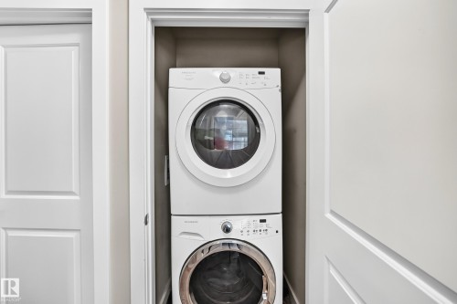 Built-in laundry closet featuring a white stacked washer and dryer unit - #10 2803 James Mowatt Trail Sw, Edmonton, AB - Indoor Photo Showing Laundry Room