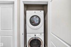 Built-in laundry closet featuring a white stacked washer and dryer unit - 