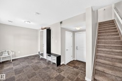 Entryway featuring durable square tile flooring, a staircase with carpeted treads, and two paneled interior doors - 