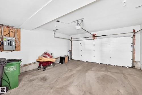 Spacious garage featuring a concrete floor and a white panel garage door with an automatic opener system - #10 2803 James Mowatt Trail Sw, Edmonton, AB - Indoor Photo Showing Garage