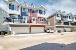 Exterior townhouse facade featuring multiple dormer windows, individual balconies with black railings, and attached garages with white doors - 