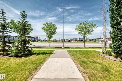 Concrete pathway framed by green lawn and various trees - #10 2803 James Mowatt Trail Sw, Edmonton, AB - Outdoor With View