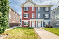 Modern townhome architecture featuring red and blue siding, white trim, and dark window shutters - 
