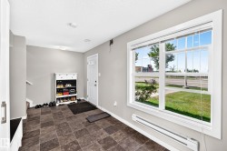 Entryway featuring neutral wall tones, large window with white trim, dark tiled flooring, and white paneled door - 