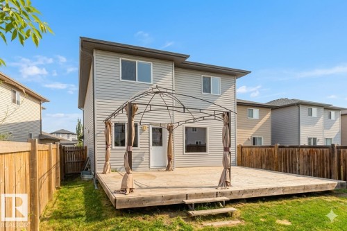 Rear exterior featuring a spacious wooden deck with a gazebo frame, a fenced yard, and light gray siding - 1919 Hammond Place, Edmonton, AB - Outdoor
