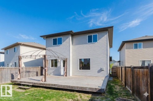 Rear exterior featuring a spacious wooden deck with a gazebo frame, a grassy yard, and horizontal siding - 1919 Hammond Place, Edmonton, AB - Outdoor With Exterior