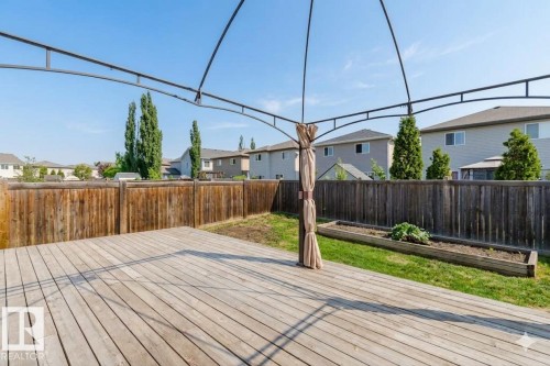 Spacious outdoor deck featuring natural wood planks, a metal-framed gazebo, and a raised garden bed - 1919 Hammond Place, Edmonton, AB - Outdoor