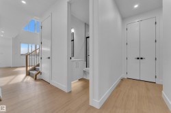 Light wood-finish flooring throughout, complemented by crisp white walls and doors - 