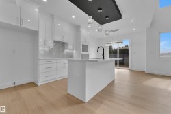 Contemporary kitchen featuring a white island with an integrated sink and matte black faucet, surrounded by sleek white cabinetry - 