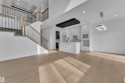 Open-concept living space with light wood-finish flooring, a contemporary staircase featuring light wood railings and black spindles, and recessed lighting throughout - 