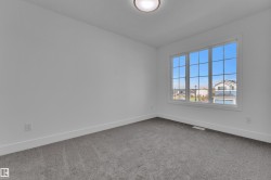 Room featuring a large multi-pane window, white walls, gray carpet, white baseboards, and a flush mount ceiling light fixture - 