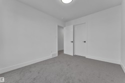 Spacious interior room with light gray carpeting and white walls - 