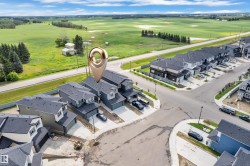 Aerial perspective showcasing a collection of modern townhomes with dark roofing and light-colored siding, featuring attached garages and concrete driveways - 
