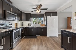 Modern kitchen featuring dark wood cabinetry, stainless steel appliances, light-toned countertops, subway tile backsplash, and wood-finish flooring - 