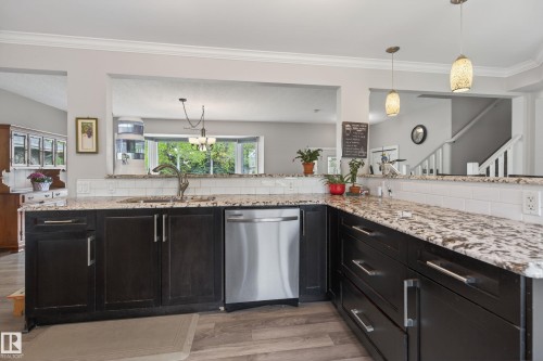 Kitchen featuring dark wood cabinetry, light-toned granite countertops, and a subway tile backsplash - 10 Abbey Crescent, St. Albert, AB - Indoor Photo Showing Kitchen With Upgraded Kitchen